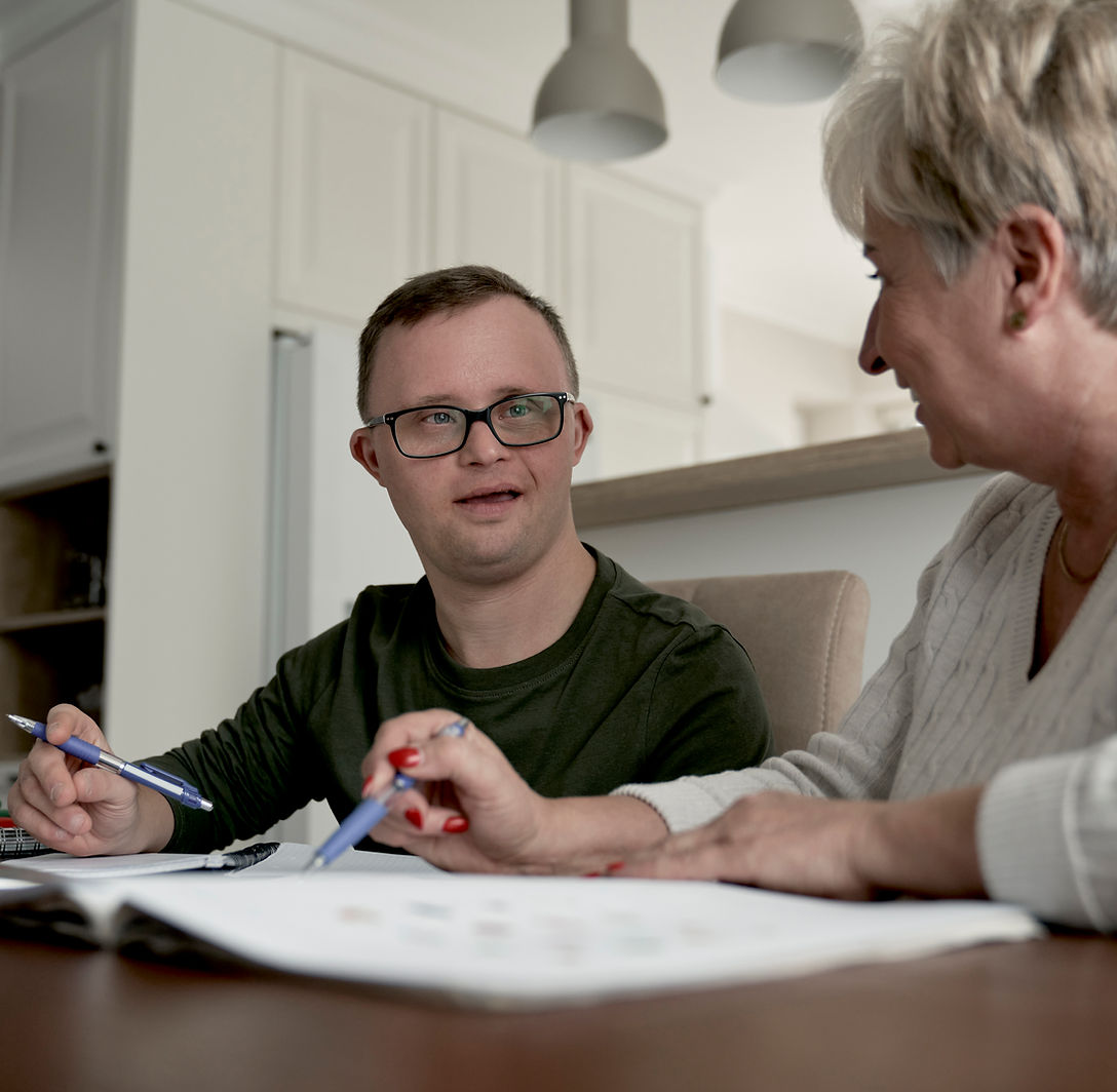 Family member and young man learning together at a kitchen table